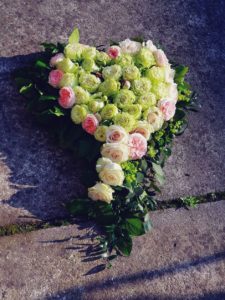 dekoracja na grób z zielonhmi i różowymi kwiatami